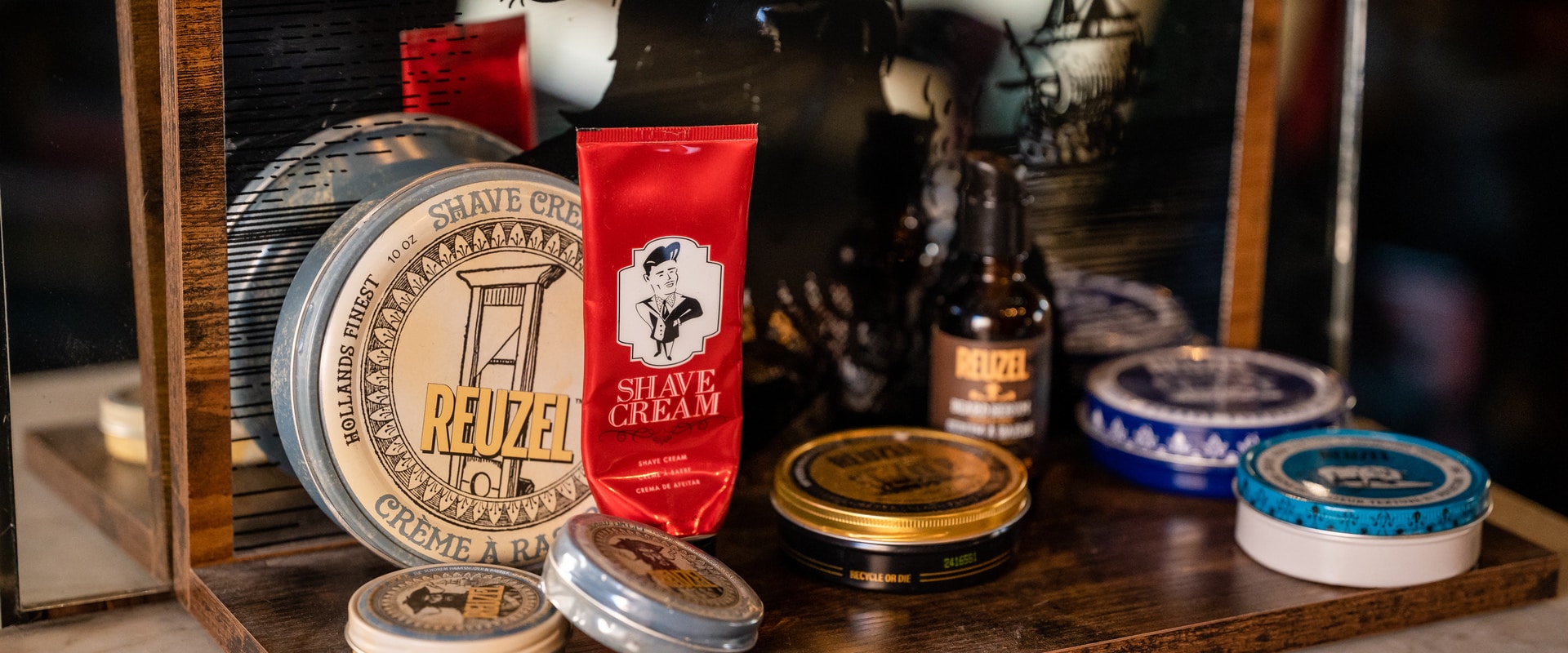 Reuzel grooming products curated on the retail shelf at the Bookcase — pomades and shave cream chosen by our barbers