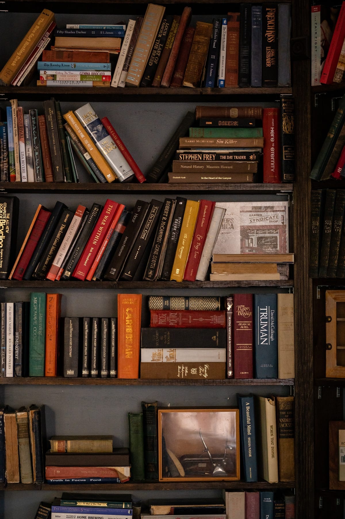 Floor-to-ceiling bookcase filled with vintage volumes — the literary roots of the Bookcase and Barber