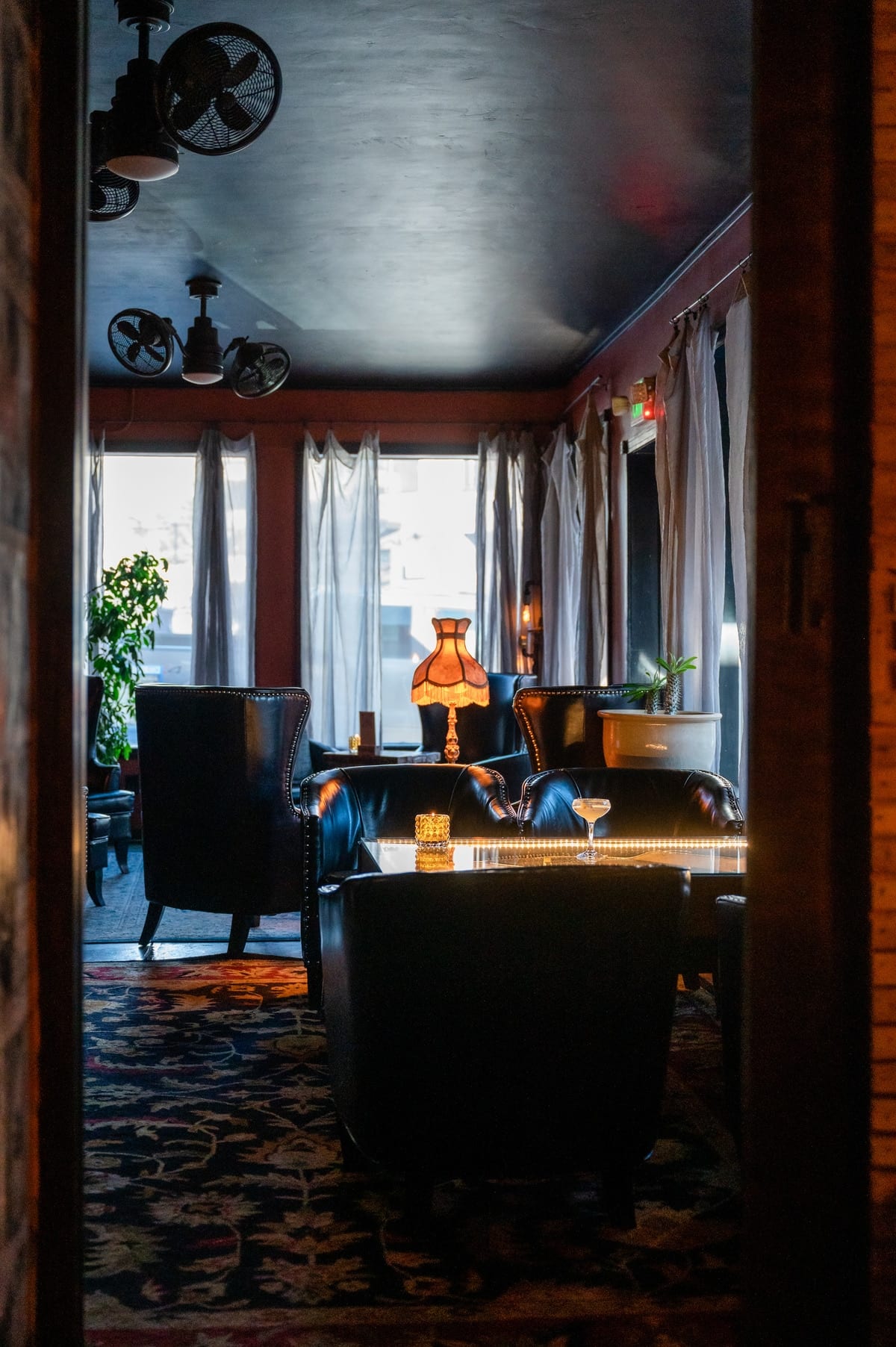 Cozy seating nook lit by a brass lamp in the speakeasy