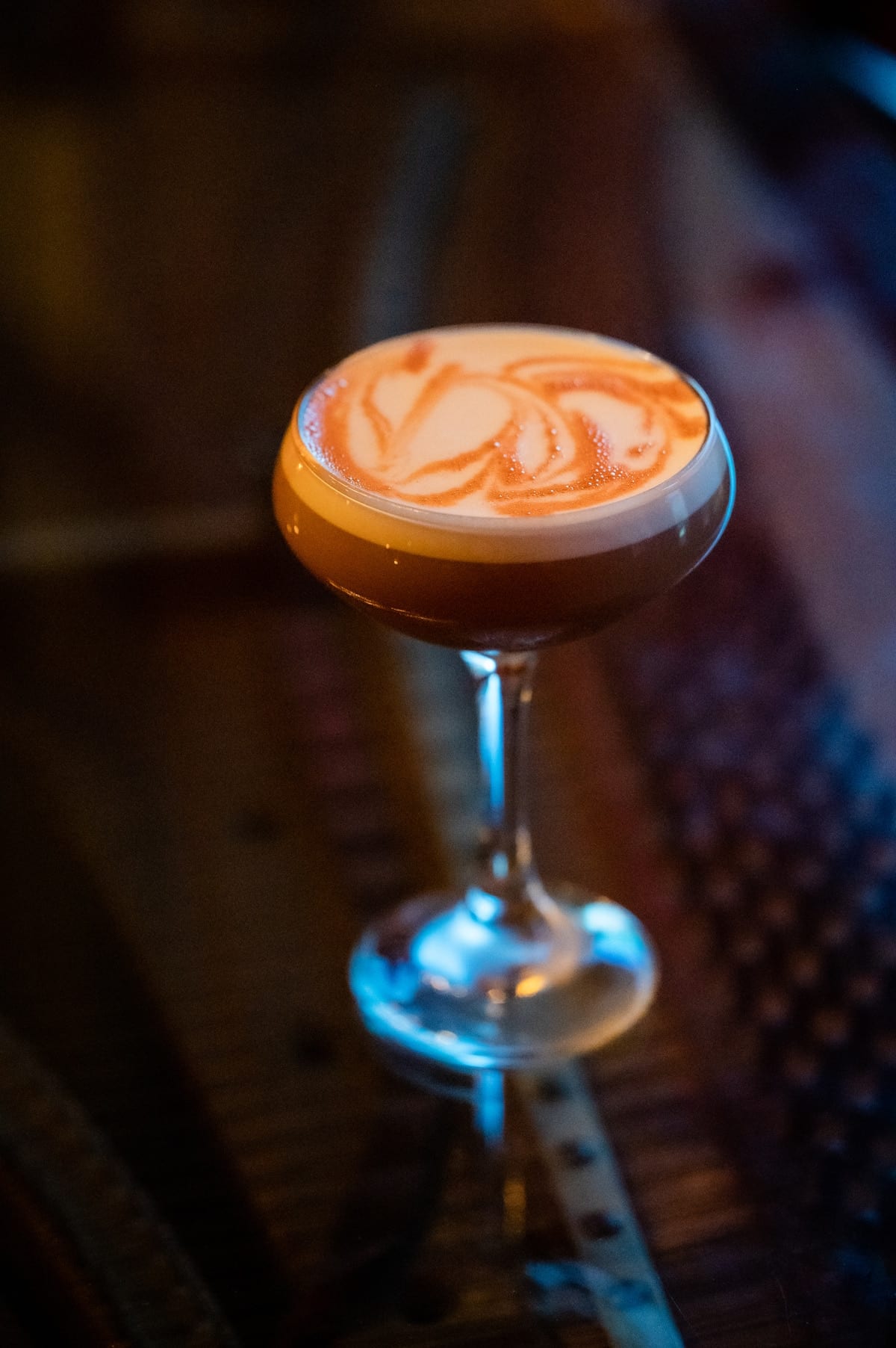 Hand-poured cocktail in a crystal coupe glass with single warm key light