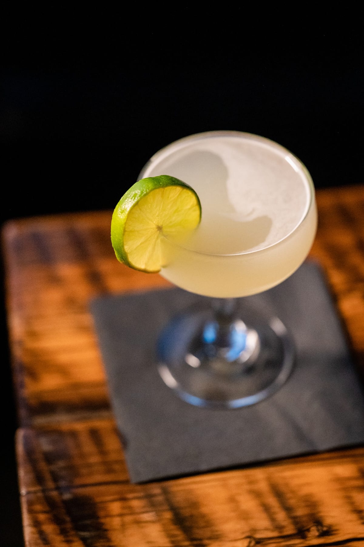 Bartender pouring a craft cocktail behind the speakeasy bar